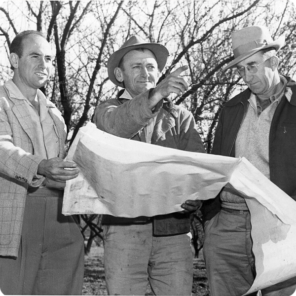 Fred Hignell with two other men holding building plans